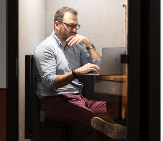 7N male staff working in a phone booth on his computer